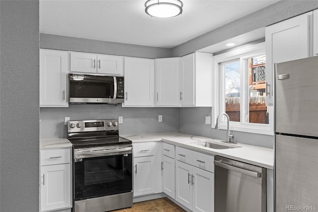 kitchen with white cabinetry, appliances with stainless steel finishes, sink, and light tile patterned floors