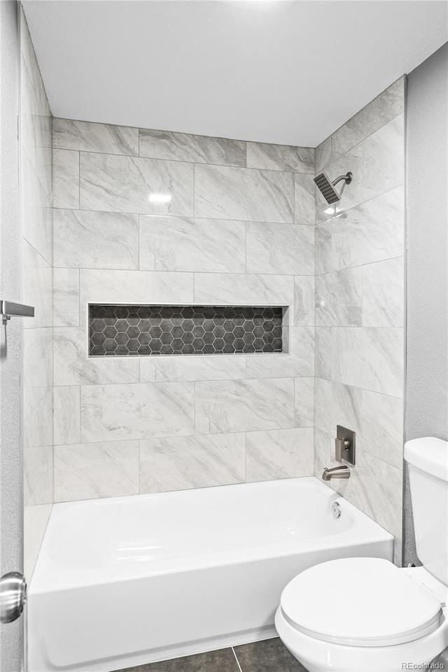 bathroom featuring tiled shower / bath combo and toilet