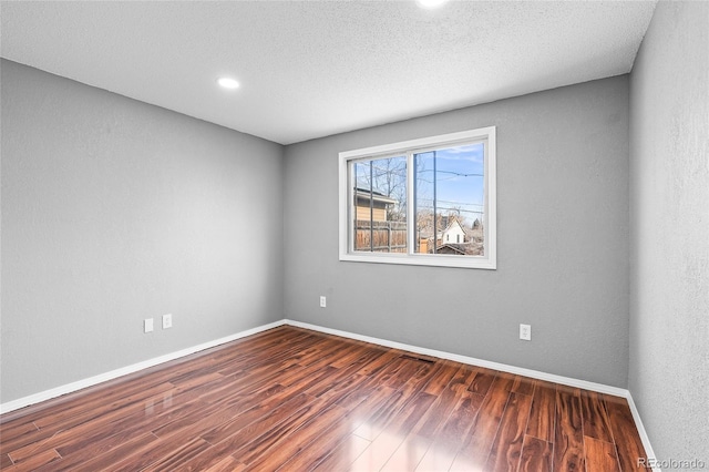 unfurnished room featuring dark wood-type flooring and a textured ceiling