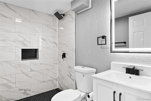 bathroom featuring vanity, toilet, and tiled shower