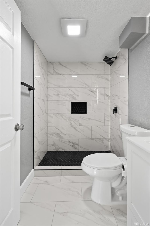 bathroom featuring tiled shower, vanity, toilet, and a textured ceiling