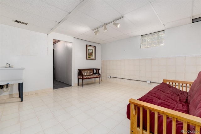 sitting room featuring tile patterned floors, track lighting, and a drop ceiling