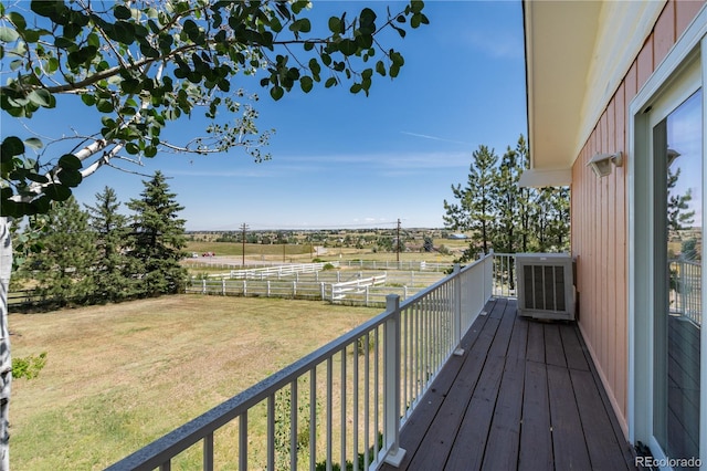 wooden terrace with a rural view, cooling unit, and a lawn