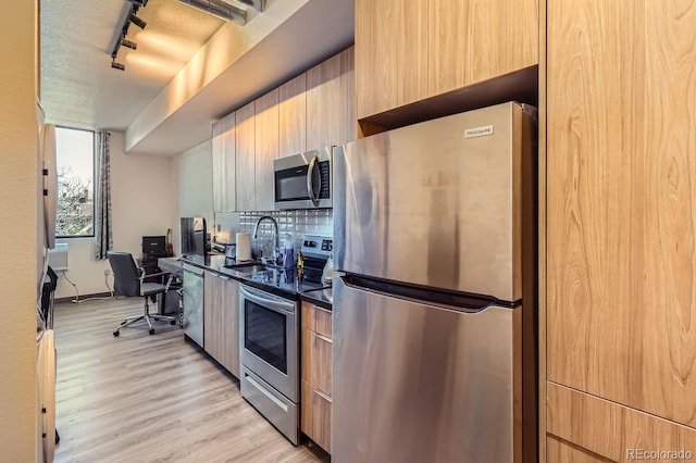 kitchen with light wood-type flooring, track lighting, a textured ceiling, stainless steel appliances, and sink