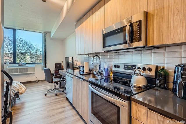 kitchen featuring decorative backsplash, appliances with stainless steel finishes, light wood-type flooring, and sink