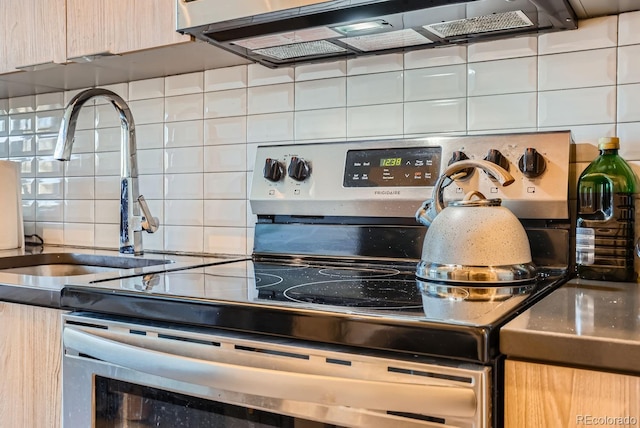 kitchen with decorative backsplash, light brown cabinets, electric stove, and sink