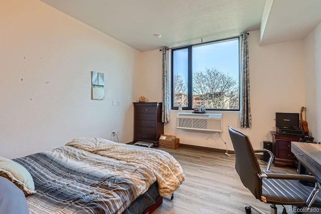 bedroom with a wall unit AC and light hardwood / wood-style floors