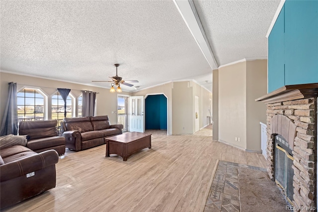 24655 2nd Ave, Eaton, CO 80615 - living area with a textured ceiling, light wood-type flooring, a fireplace, a ceiling fan, and plenty of natural light