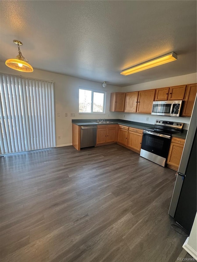 kitchen featuring sink, a textured ceiling, dark hardwood / wood-style floors, pendant lighting, and appliances with stainless steel finishes