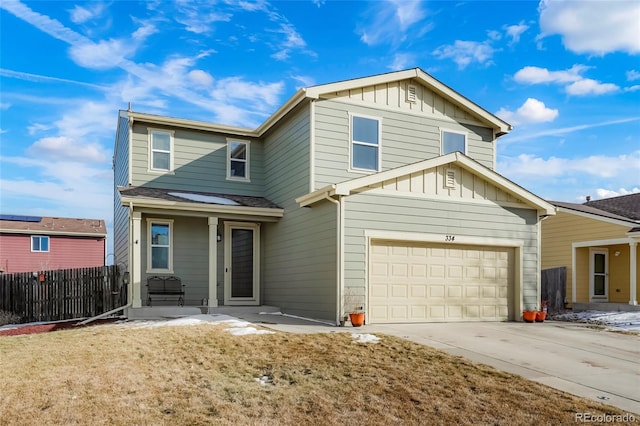 traditional home with a garage, concrete driveway, fence, board and batten siding, and a front yard