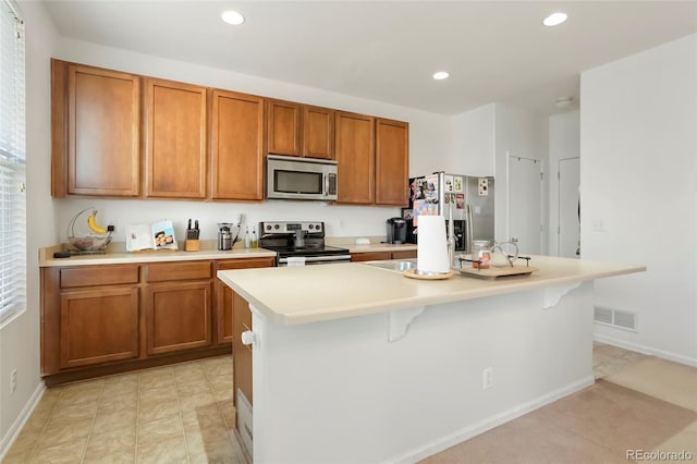 kitchen featuring appliances with stainless steel finishes, a breakfast bar area, and a center island with sink