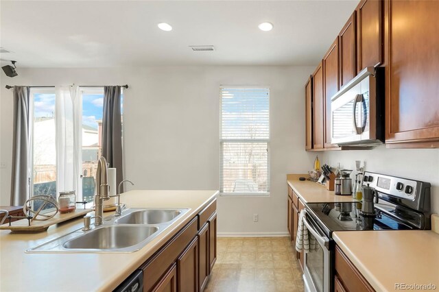 kitchen with appliances with stainless steel finishes, light countertops, a sink, and visible vents