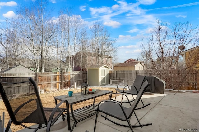 view of patio featuring an outbuilding, a shed, outdoor dining area, and a fenced backyard