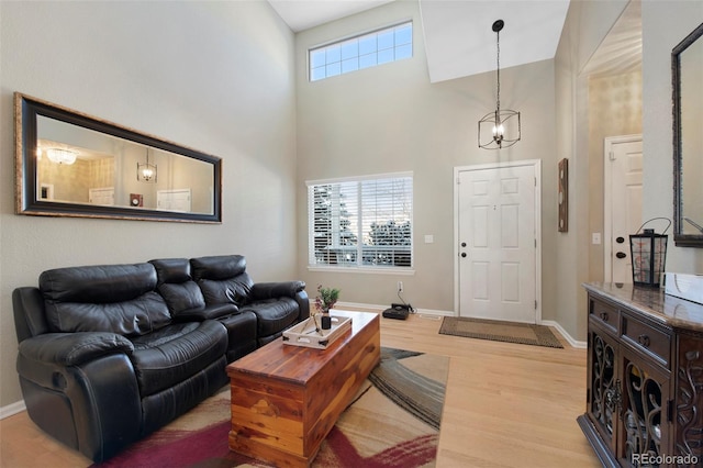 living room featuring light wood-type flooring and a towering ceiling