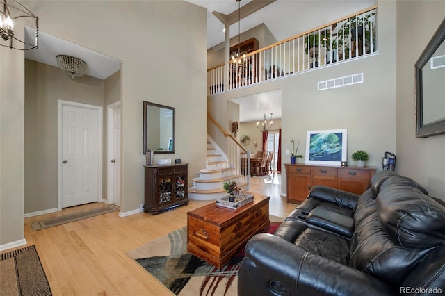 living room featuring a high ceiling, an inviting chandelier, and light hardwood / wood-style floors