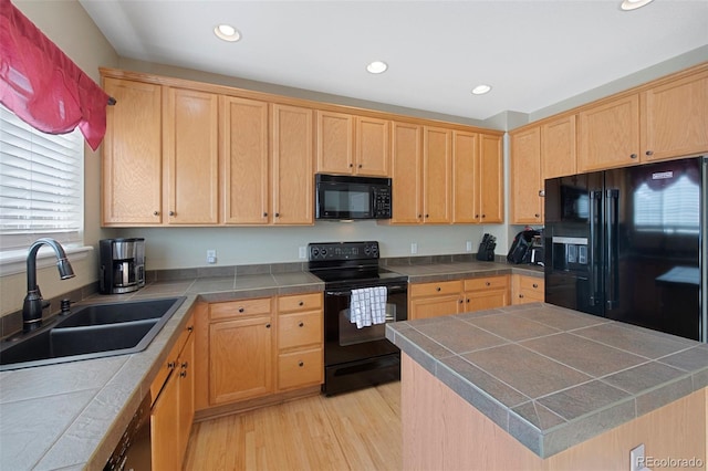 kitchen featuring tile countertops, light brown cabinets, black appliances, light hardwood / wood-style flooring, and sink