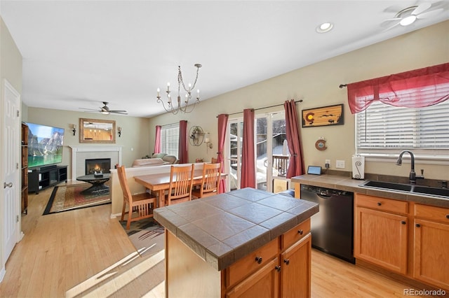 kitchen featuring a kitchen island, sink, black dishwasher, light wood-type flooring, and tile counters