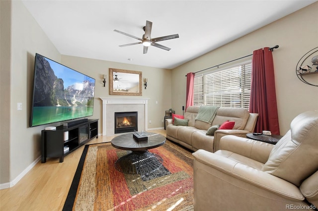 living room with light hardwood / wood-style floors, ceiling fan, and a tiled fireplace