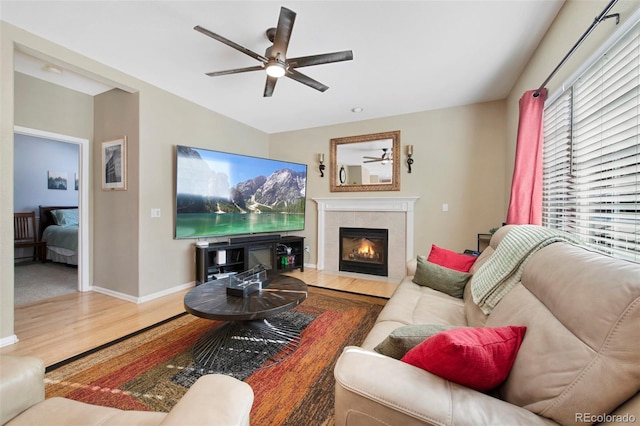 living room featuring ceiling fan, wood-type flooring, and a fireplace