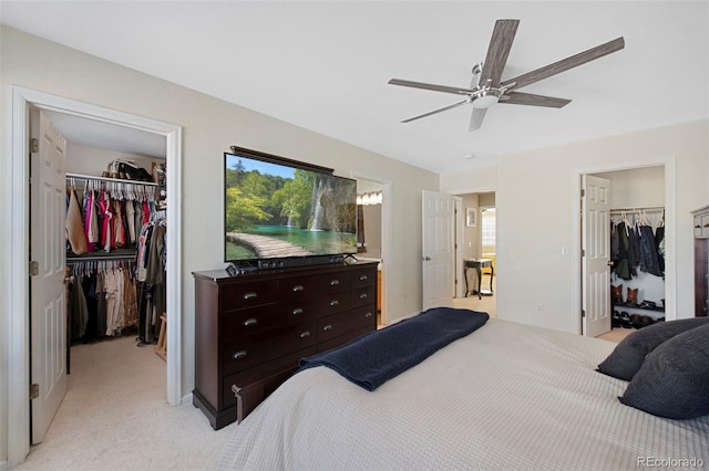 bedroom with light carpet, ceiling fan, two closets, and multiple windows