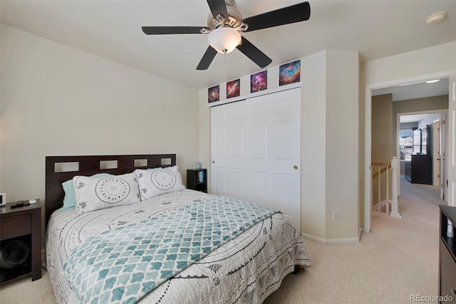 bedroom with ceiling fan, light colored carpet, and a closet