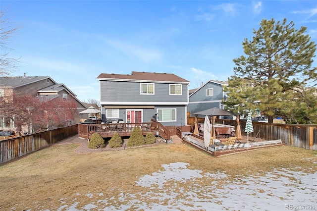 back of house with a wooden deck, a jacuzzi, and a lawn