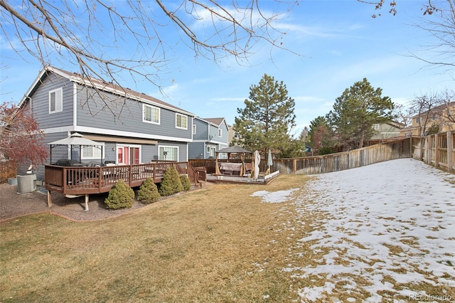 snow covered back of property with central AC, a wooden deck, a gazebo, and a lawn