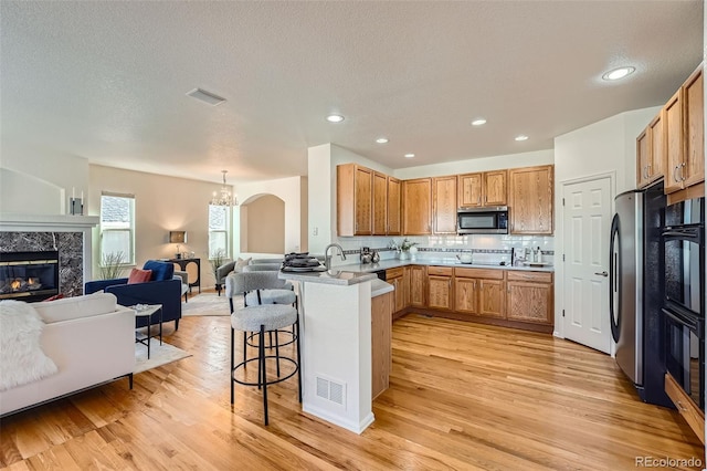 kitchen featuring light hardwood / wood-style flooring, backsplash, a kitchen breakfast bar, stainless steel appliances, and kitchen peninsula