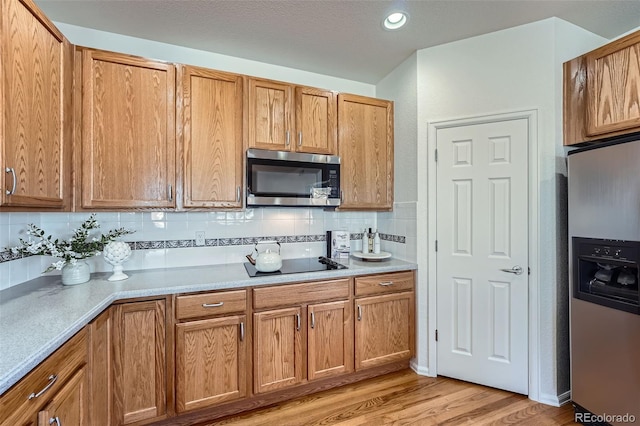 kitchen with tasteful backsplash, stainless steel appliances, and light wood-type flooring