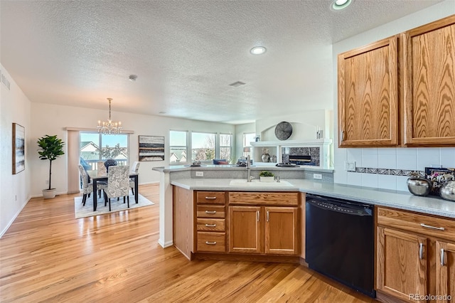 kitchen with tasteful backsplash, dishwasher, sink, light hardwood / wood-style floors, and a textured ceiling