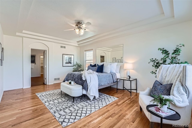 bedroom with a tray ceiling, ceiling fan, and hardwood / wood-style flooring