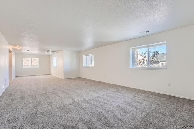 carpeted empty room featuring plenty of natural light, a textured ceiling, and ceiling fan