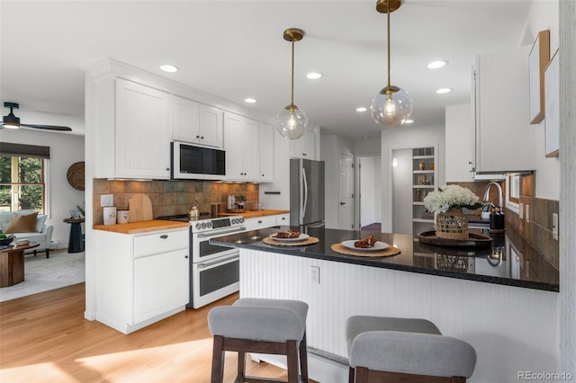 4185 Red Rock Dr, Larkspur, CO 80118 - kitchen featuring freestanding refrigerator, range with two ovens, white microwave, white cabinets, and a peninsula