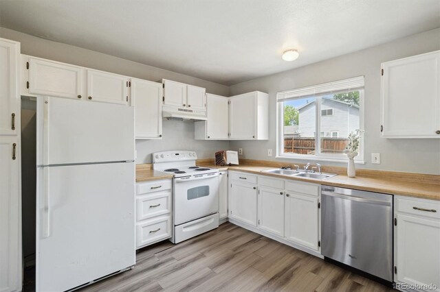 kitchen with white appliances, under cabinet range hood, a sink, white cabinetry, and light countertops