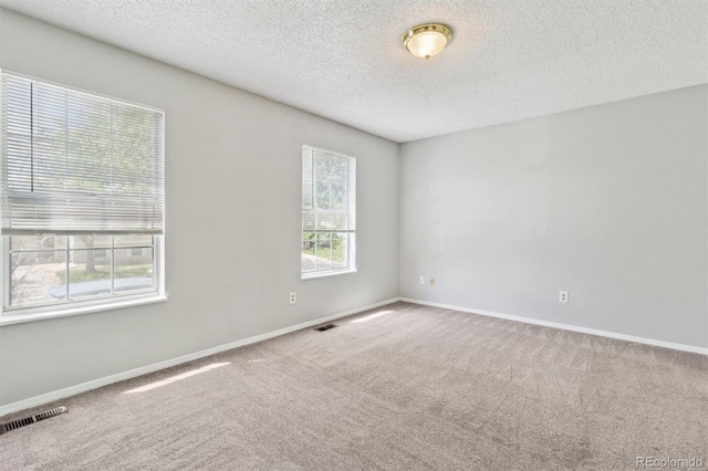 unfurnished room with a textured ceiling, carpet floors, and baseboards