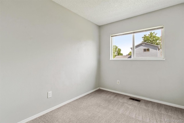 carpeted empty room with baseboards and a textured ceiling