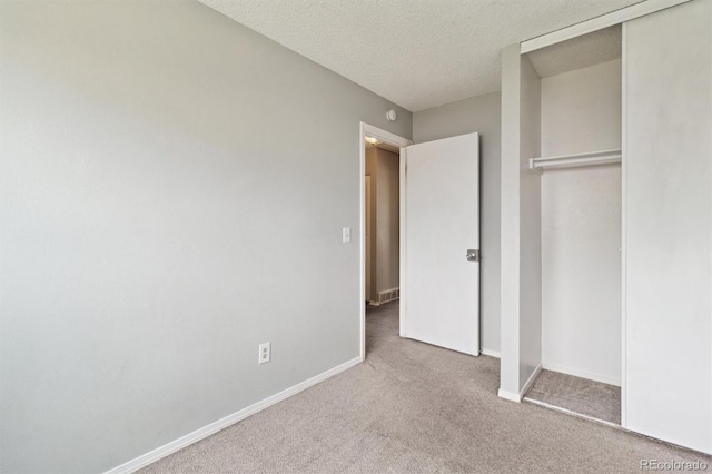 unfurnished bedroom featuring carpet, a closet, baseboards, and a textured ceiling