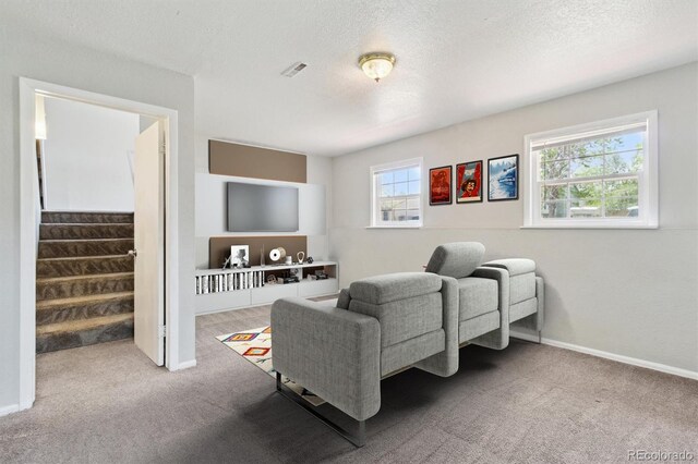 carpeted living room with stairs, a textured ceiling, and baseboards