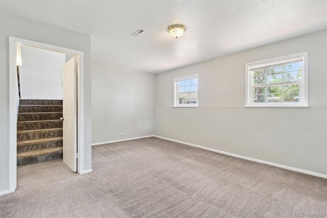 unfurnished bedroom with carpet flooring, baseboards, and a textured ceiling