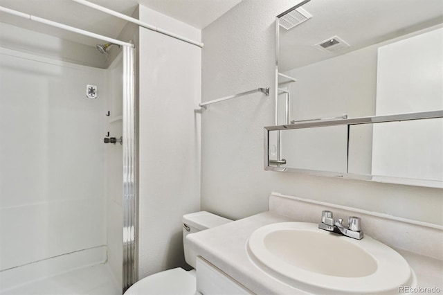bathroom with a stall shower, toilet, and vanity
