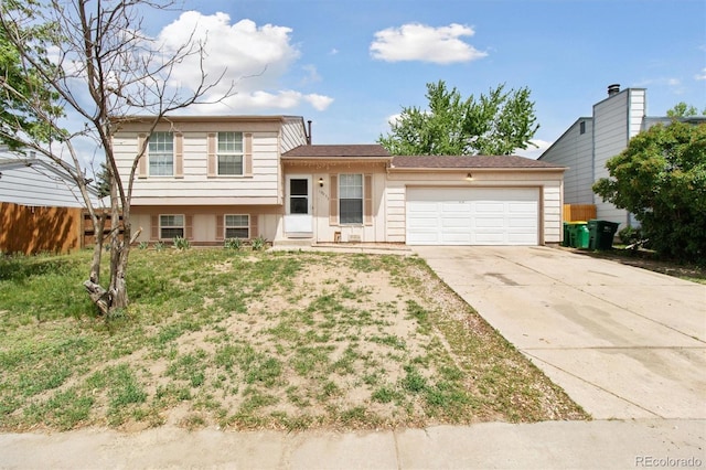 tri-level home featuring an attached garage, driveway, and fence