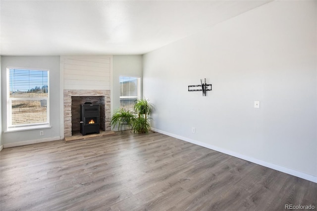 unfurnished living room with hardwood / wood-style floors, lofted ceiling, and a wood stove