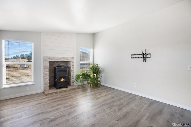 unfurnished living room featuring light wood-type flooring, a wood stove, and vaulted ceiling