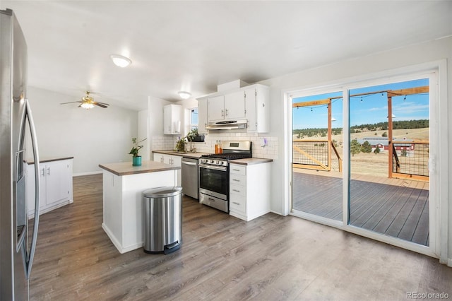 kitchen with white cabinetry, hardwood / wood-style floors, decorative backsplash, a kitchen island, and appliances with stainless steel finishes