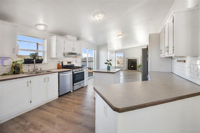 kitchen featuring kitchen peninsula, appliances with stainless steel finishes, white cabinetry, and sink