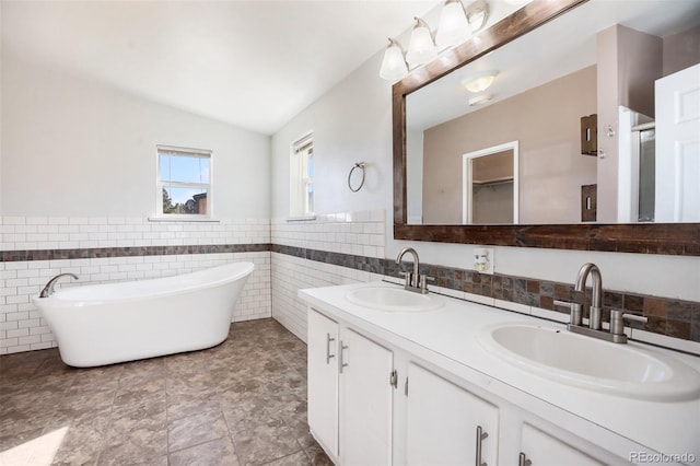 bathroom featuring vanity, lofted ceiling, tile walls, and a tub