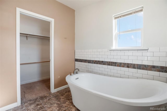 bathroom featuring a bath and tile walls