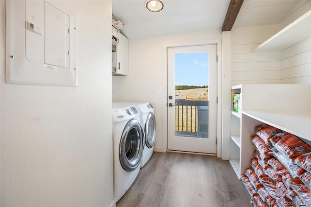 laundry room with washing machine and clothes dryer, electric panel, cabinets, and light hardwood / wood-style floors