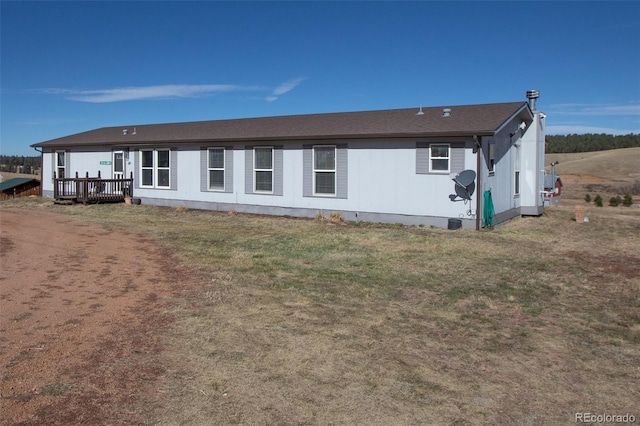 rear view of property featuring a lawn and a deck