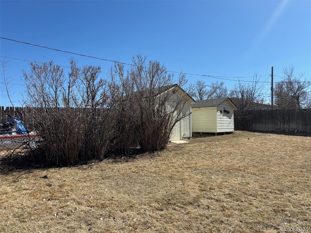 view of yard with a storage shed, an outdoor structure, and fence